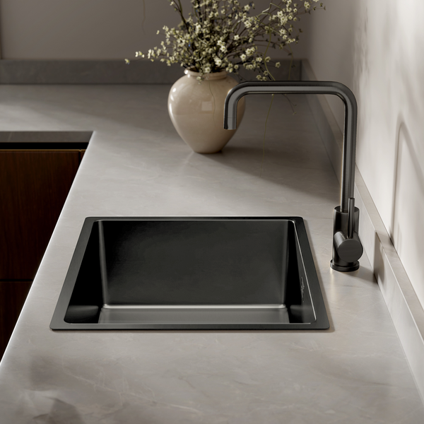 Moderne schwarze Einbauspüle mit passender Küchenarmatur in einer hellen Arbeitsplatte mit Steinoptik und Blumenvase.