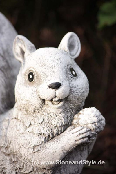 Dekorative Eichhörnchen Gartenfigur aus Stein mit Nuss in den Pfoten für die Gartendekoration.