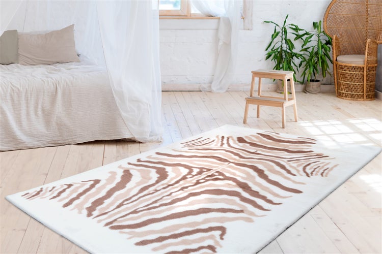 Rechteckiger Teppich mit Zebra-Muster in Braun und Beige in einem hellen Schlafzimmer mit Holzboden und Rattanmöbeln.