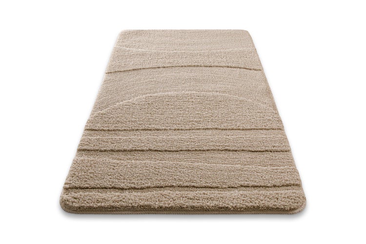 Rechteckige Badematte in Beige mit strukturiertem Wellenmuster und weichem Flor.