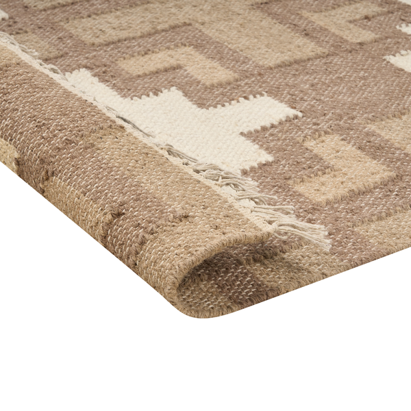 Nahaufnahme eines gewebten Teppichs mit geometrischem Muster und Fransen, zeigt die Struktur und Rückseite.