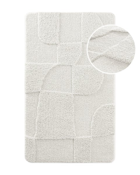 Weiße Badematte mit geometrischem Hoch-Tief-Muster und Detailansicht der weichen Textur.