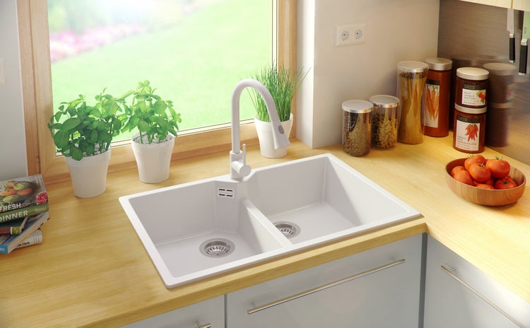 Doppelspülbecken aus hellem Material mit Wasserhahn in einer hellen Küche.