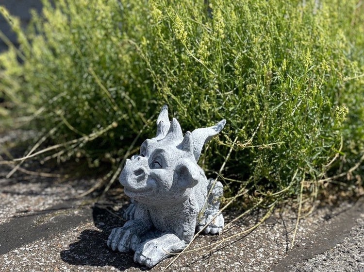 Dekorative Gartenfigur in Form eines sitzenden kleinen Drachen aus wetterfestem Material zur Dekoration im Außenbereich.