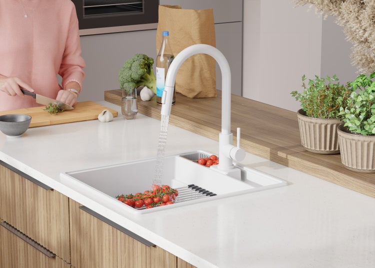 Küchenszene mit Spüle, Armatur und Person beim Gemüseschneiden