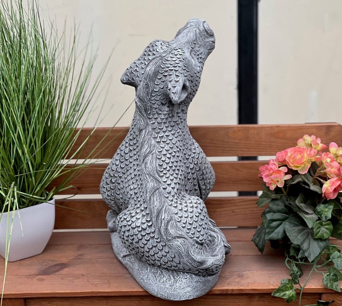 Gartenfigur Drache aus Steinguss, sitzende Fabelkreatur mit Schuppenmuster, blickt nach oben, auf einer Holzbank dekoriert.