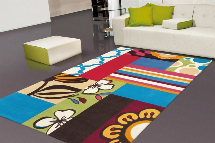 Bunter Teppich im Patchwork-Design mit Blumen-, Streifen- und Punktmustern in einem modernen Wohnzimmer mit weißem Sofa.