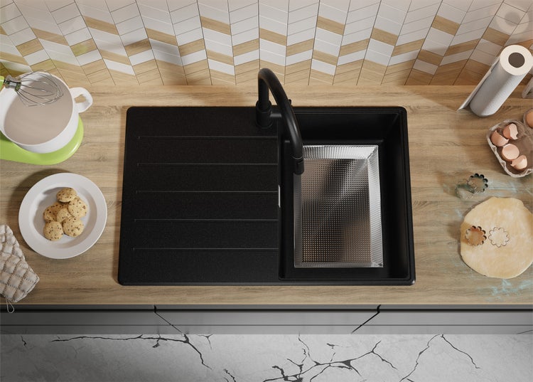 Ansicht von oben auf eine schwarze Küchenspüle mit Abtropffläche, Armatur, Gebäck und Backutensilien auf einer Arbeitsplatte