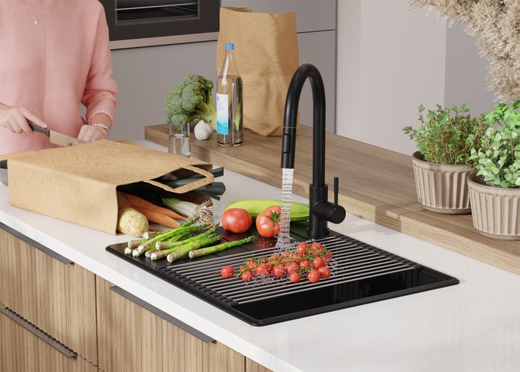 Küchenszene mit Spüle, Armatur, Gemüse und einer Person, die Gemüse schneidet