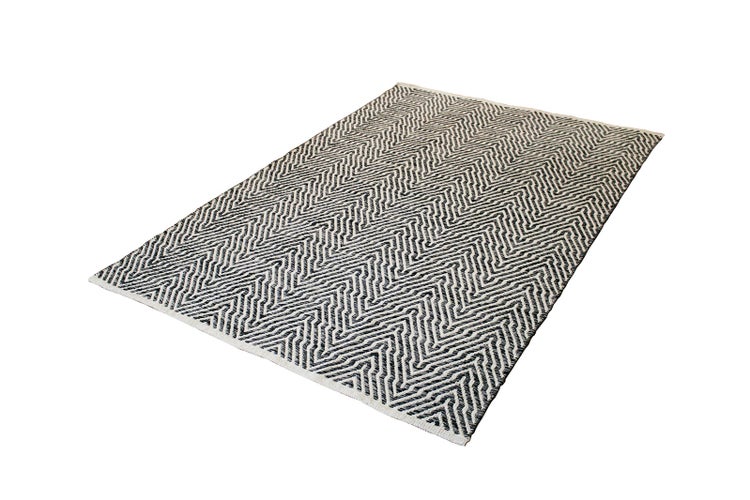 Flachgewebter Teppich mit geometrischem Muster in Schwarz und Weiß.