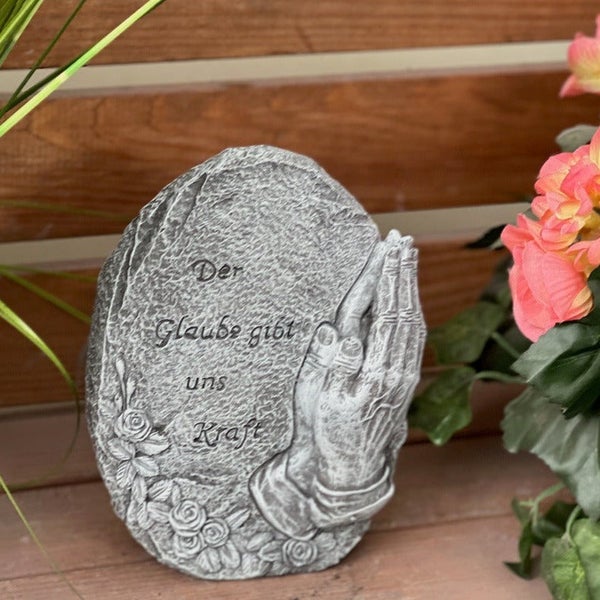 Grabstein aus Kunststein mit betenden Händen und Rosenrelief und der Inschrift Der Glaube gibt uns Kraft als Grabschmuck.