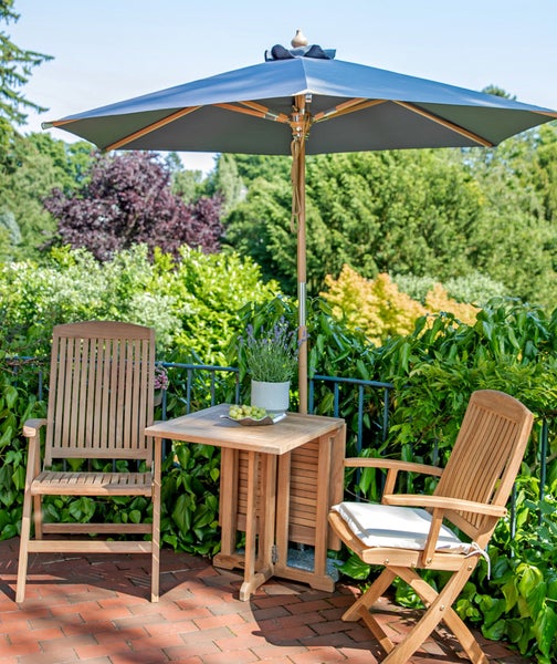 Gartenszene mit zwei Holzstühlen, einem Holztisch, einem Sonnenschirm und Pflanzen im Freien