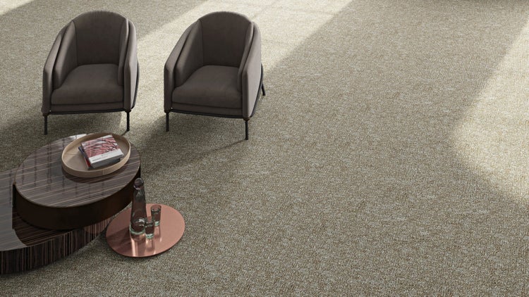 Moderner Wohnraum mit großflächigem, strukturiertem Teppichboden, zwei Sesseln und einem abgestuften Couchtisch in einem hellen Ambiente.