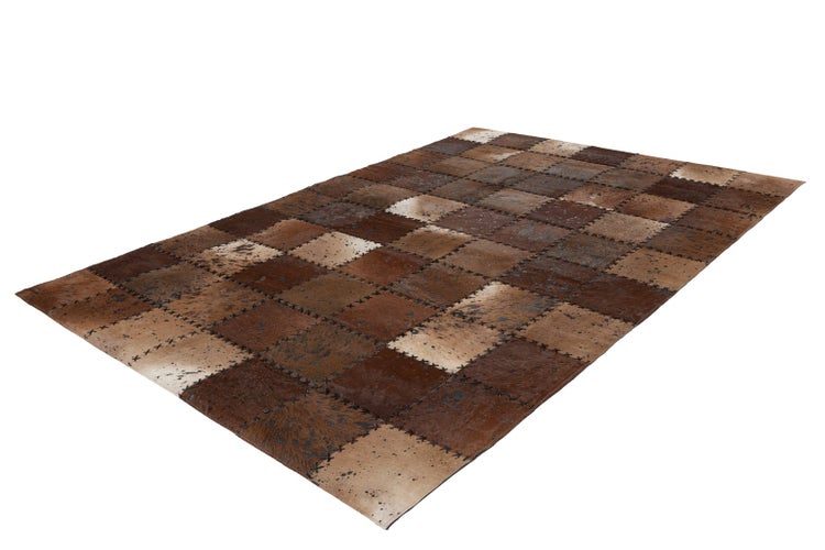 Patchwork-Teppich aus Kuhfell-Quadraten mit Ziernähten in verschiedenen Brauntönen.