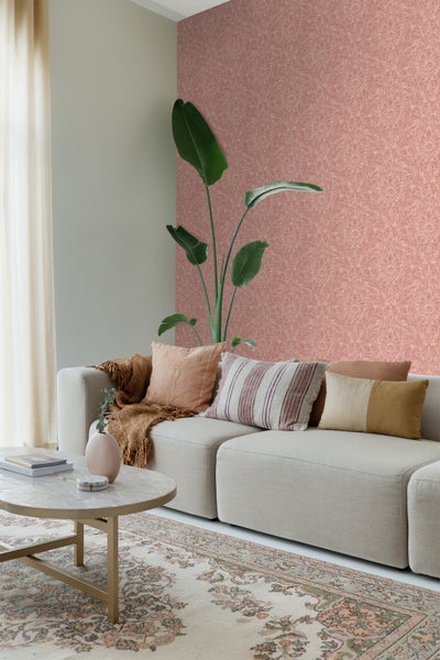 Wohnzimmer mit Couch, Kissen, Tisch, Teppich und gemusterter Tapete