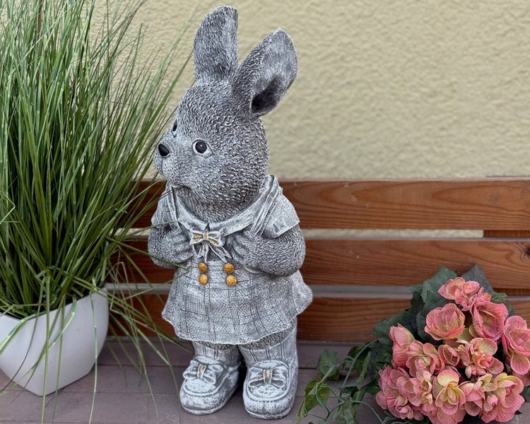 Dekorative Gartenfigur in Form eines stehenden Hasen in Kleidung.