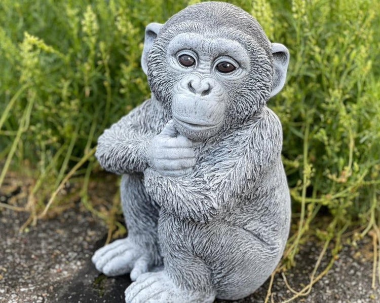 Dekorative Gartenfigur in Form eines sitzenden Schimpansen aus wetterfestem Kunststein für den Außenbereich.