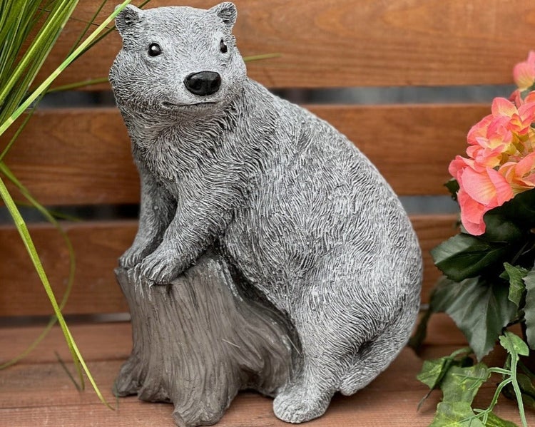 Witterungsbeständige Gartenfigur aus Kunststein in Form eines Wombats auf einem Baumstumpf als dekoratives Element für den Außenbereich.