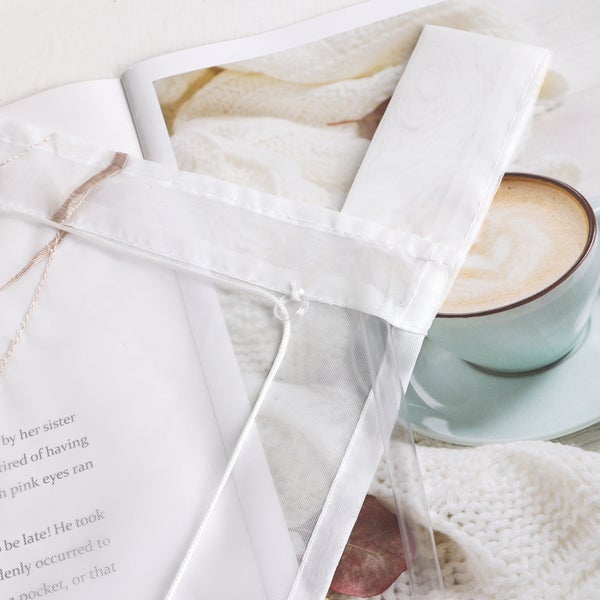 Szene mit einer transparenten Gardine, einer Zeitschrift und einer Tasse Kaffee