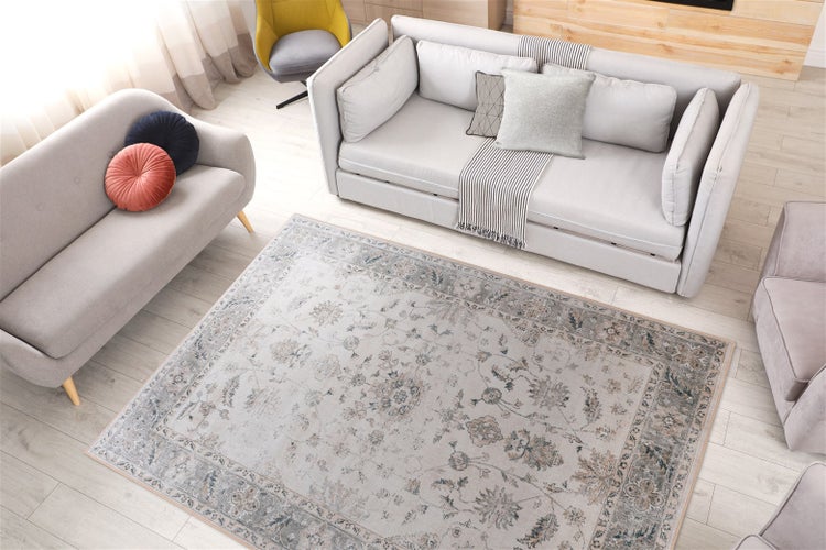 Teppich mit orientalischem Muster im hellen Wohnzimmer mit grauen Sofas und hellem Holzboden.