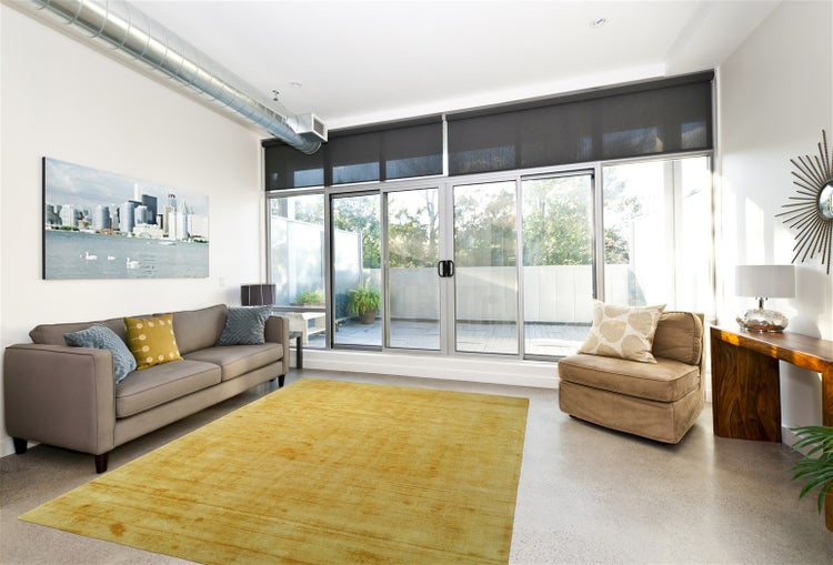 Nahaufnahme eines goldfarbenen Teppichbodens mit fein gerippter Oberflächenstruktur.