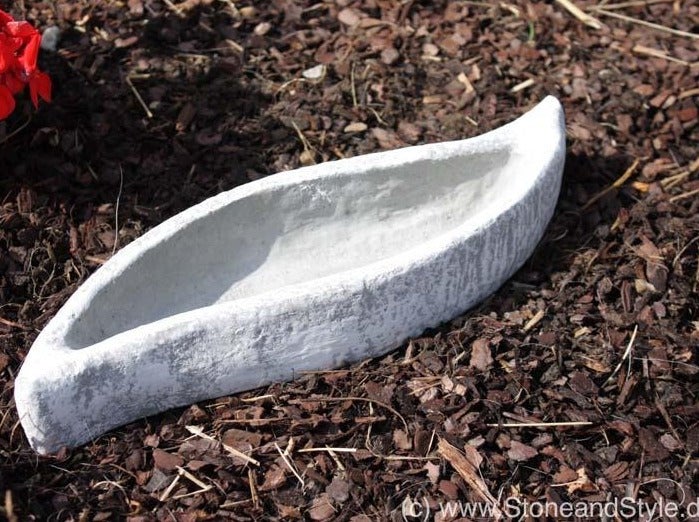 Längliche Pflanzschale in Bootsform aus Stein für den Garten.