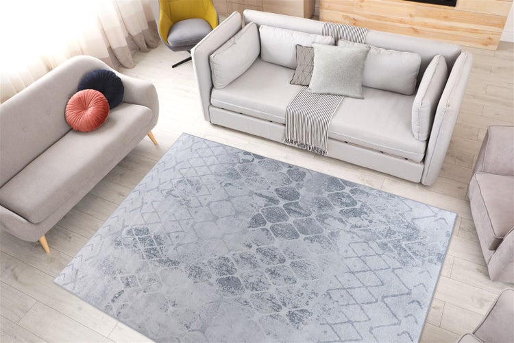 Rechteckiger Teppich mit modernem, geometrischem Muster im Vintage-Stil in einem hell eingerichteten Wohnzimmer auf Holzboden.