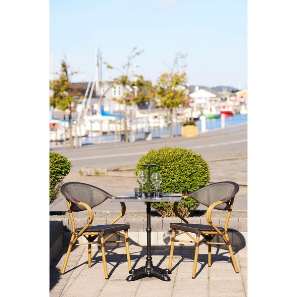 Szene mit Gartentisch, zwei Stühlen und zwei Weingläsern im Freien.