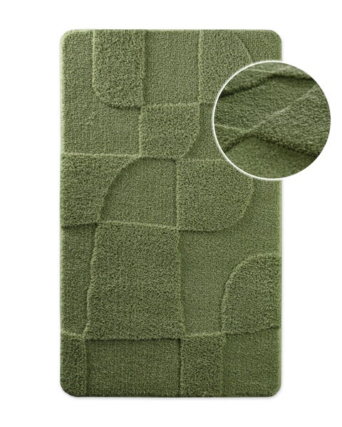 Rechteckige grüne Badematte mit geometrischem Reliefmuster und Detailansicht der Hochflor Oberfläche.