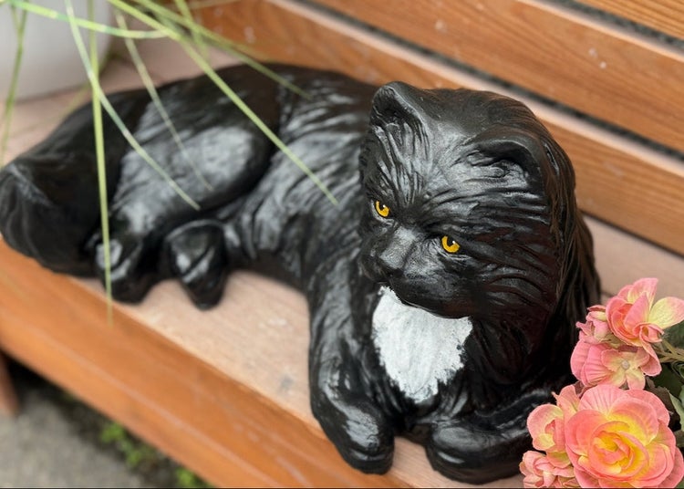 Dekorative Katzenfigur für den Garten aus wetterfestem Material in liegender Position.