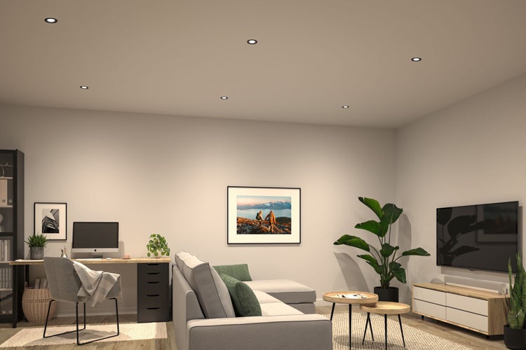 Modern eingerichtetes Wohnzimmer mit integriertem Arbeitsbereich, Einbaustrahlern an der Decke, Sofa, Couchtischen und TV-Möbel.