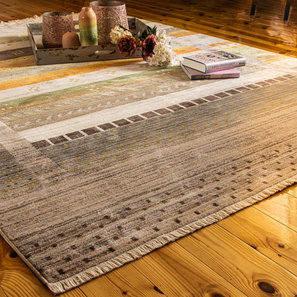 Rechteckiger Webteppich mit Fransen und geometrischem Muster in Erdtönen auf Holzfußboden mit einem Dekotablett in einem hellen Wohnzimmer.