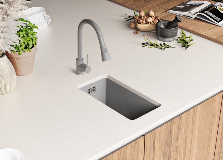 Küchenspüle aus Stein mit Wasserhahn auf einer Küchentheke.