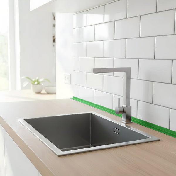 Moderne Küchenspüle aus Edelstahl mit Einhebelmischbatterie in einer Küche mit heller Holzoberfläche und weißen Wandfliesen.