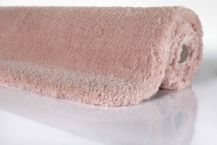 Flauschige Badematte mit hohem Flor, aufgerollt, rosa.