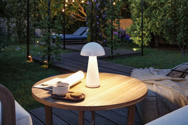Gartenszene mit beleuchtetem Tisch und Lampe im Außenbereich