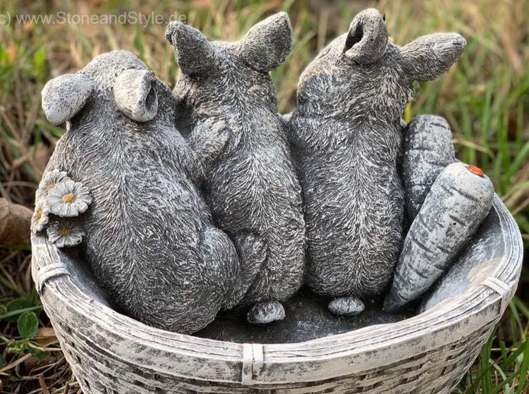 Steinfigur als Korb mit drei sitzenden Hasen und einer Karotte zur Gartendekoration