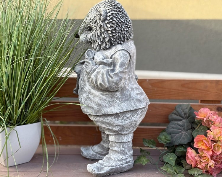 Gartenfigur aus Steinguss in Form eines stehenden Igels in Kleidung, grau patiniert.
