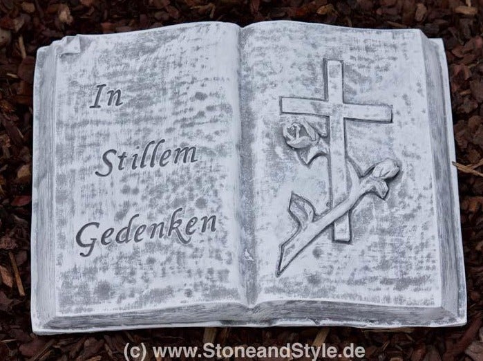 Grabschmuck in Form eines aufgeschlagenen Buches mit der Inschrift In stillem Gedenken und einem Relief von einem Kreuz mit Rose.