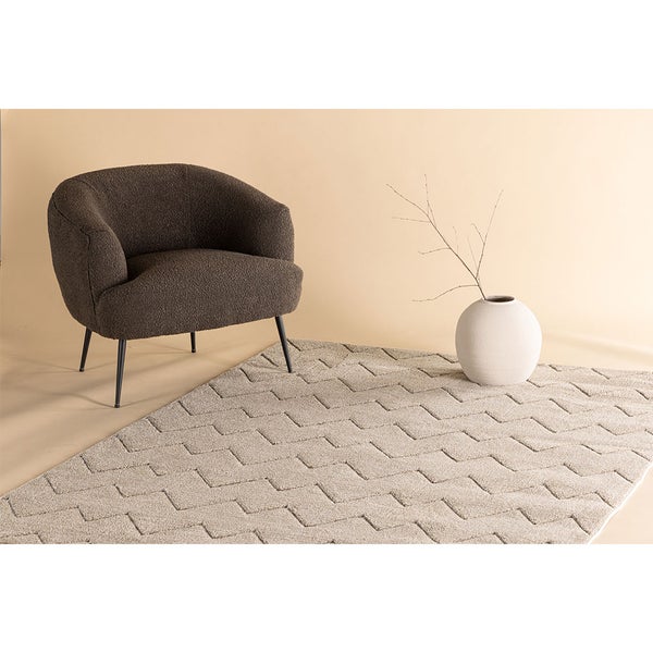 Szene mit einem Sessel, einer Vase mit Zweigen und einem Teppich mit Muster