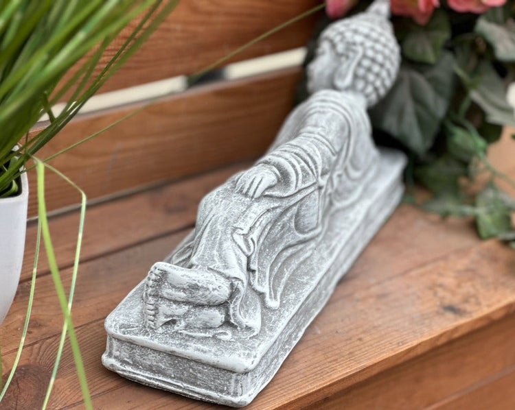 Liegende Buddha-Figur aus Stein für die Gartendekoration auf einer Holzoberfläche