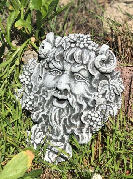 Wandmaske aus Stein als dekoratives Gartenrelief mit einem Waldgeist Motiv umgeben von Weinblättern und Trauben.