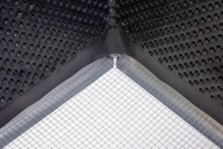 Detailaufnahme einer Noppenbahn aus Kunststoff und eines feinmaschigen Drahtgitters aus Metall.
