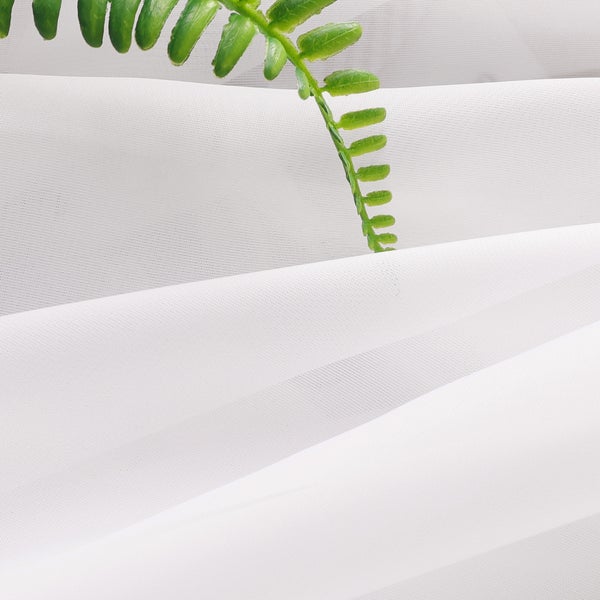 Nahaufnahme von durchscheinendem, weich fallendem Gardinenstoff mit einem grünen Blatt