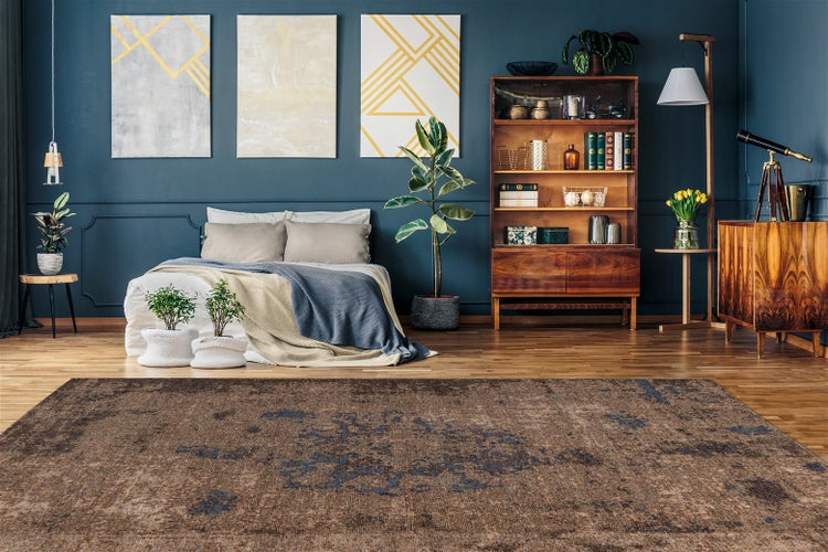 Organisiertes Zimmer im modernen Design mit braunem Teppich mit blauem Vintage-Muster auf Holzparkett, dunkelblauen Wänden, Bett und Holzregalen.