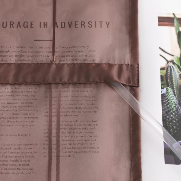 Dekoschals mit aufgedruckten Texten und Zitat neben einer Zimmerpflanze