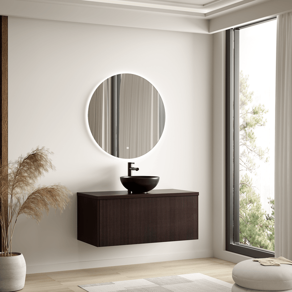 Modernes Badezimmer mit rundem LED-Spiegel, schwarzem Aufsatzwaschbecken und dunkelbraunem, wandhängendem Waschtischunterschrank mit Lamellenfront.