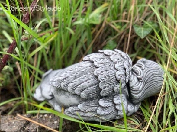 Steinfigur schlafender Engel in Graslandschaft als Gartendekoration