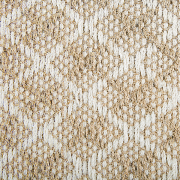 Gewebter Teppich mit Rautenmuster auf hellem Holzboden in einem hellen Schlafzimmer neben einem Bett und einem kleinen Regal.