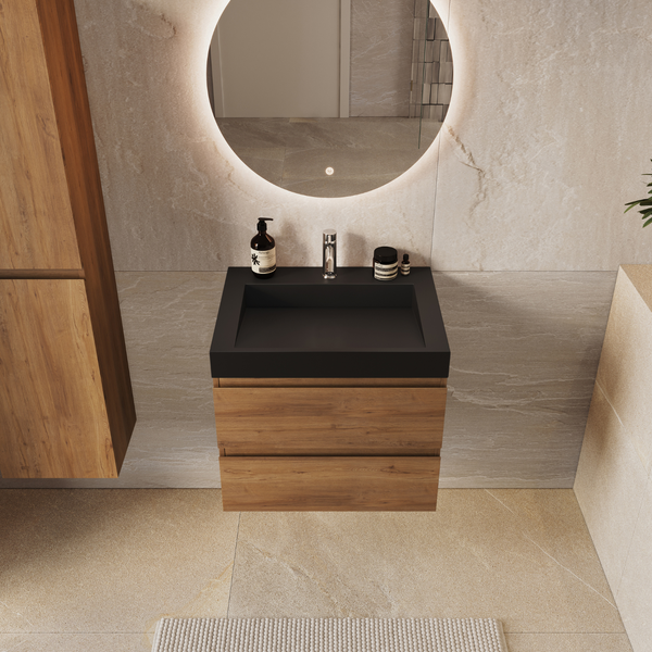 Modernes Badezimmer mit Waschtischunterschrank aus Holz, schwarzem Waschbecken, Armatur und beleuchtetem runden Spiegel vor Steinwand.